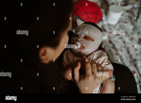 Mother looking at her newborn girl with eczema face mask Stock Photo ...