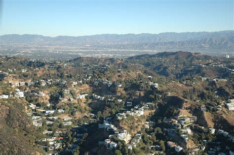 an aerial view of a city with mountains in the back ground and trees to ...