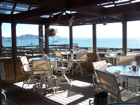 an outdoor dining area overlooking the ocean with tables and chairs set ...