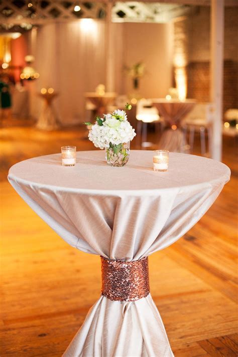 a white table topped with a vase filled with flowers on top of a wooden ...