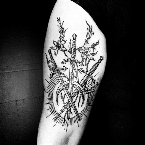 a black and white photo of a tattoo on the arm with swords, flowers and ...