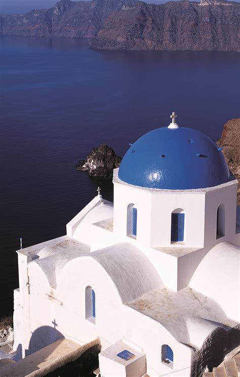 Blue Dome on White Building by the Ocean with Mountains in the Background