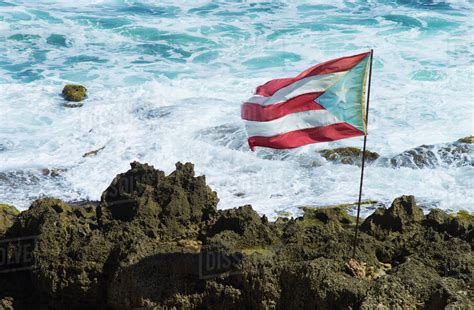 Puerto Rico, Old San Juan, Puerto Rican flag on rock with sea in ...