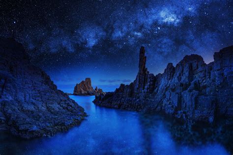 HD Wallpaper: Mystical Blue Night with Starry Sky and Rocky Coastline