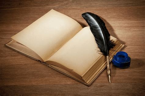 an open book with a pen and quill resting on it next to a feather