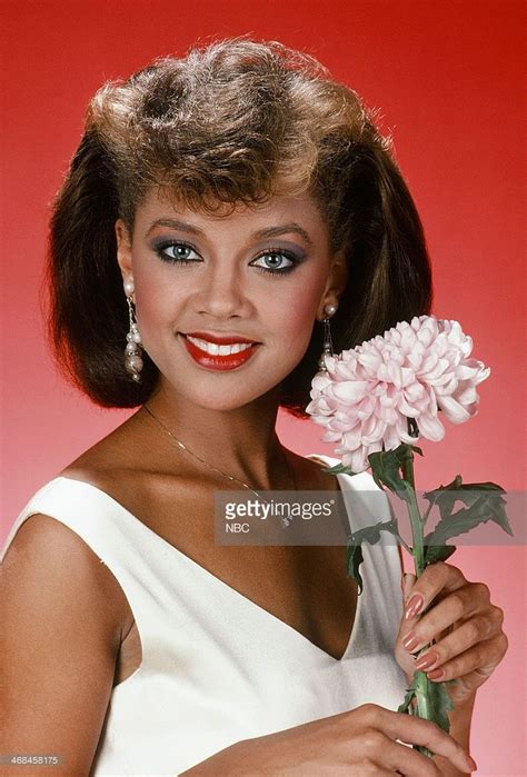 a woman holding a pink flower in her right hand and smiling at the ...