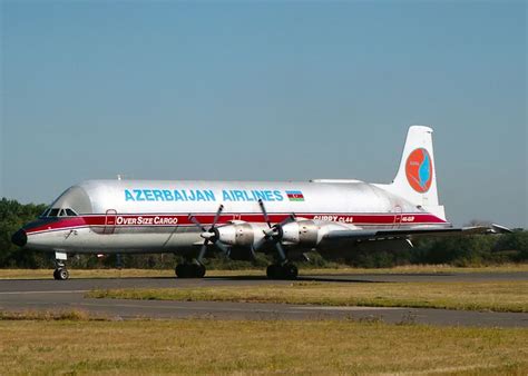 an airplane that is sitting on the runway in front of some grass and trees,