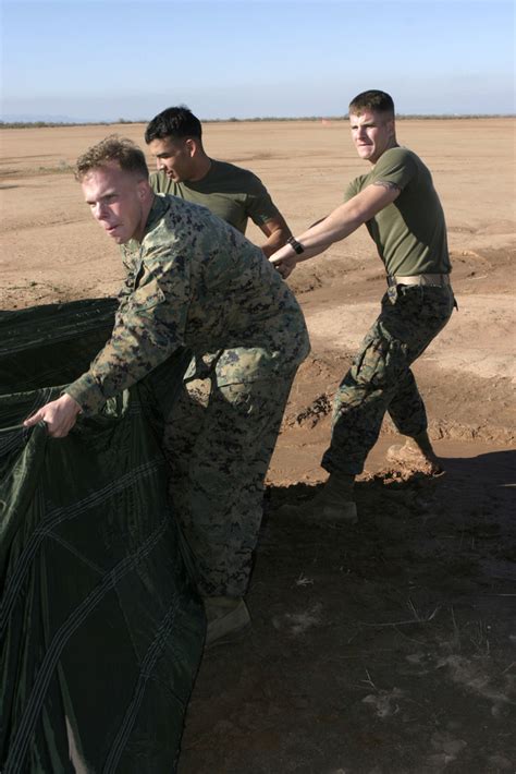 Three U.S. Marine Corps parachute riggers recover a parachute during ...