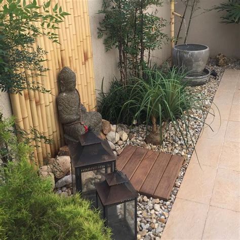 a small garden with rocks, plants and a lantern