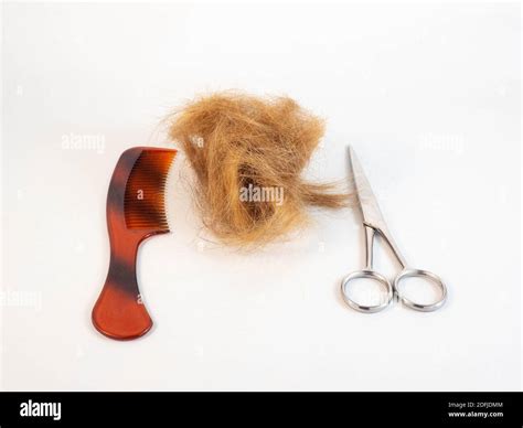 A tuft of hair after being cut, laid next to a pair of scissors, comb ...