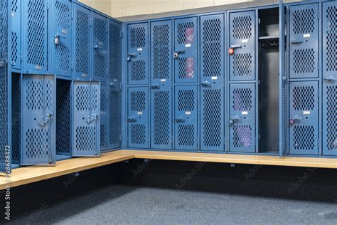 Blue metal cage lockers in a locker room with some doors open and some ...