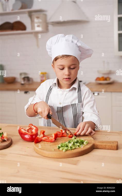 Cute little boy cooking in modern kitchen at home. Boy cook cuts ...