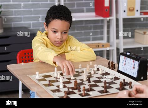 Little African-American boy playing chess during tournament in club ...