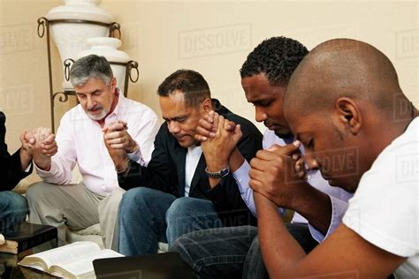 A Group Of Men Praying Together With An Open Bible - Stock Photo - Dissolve