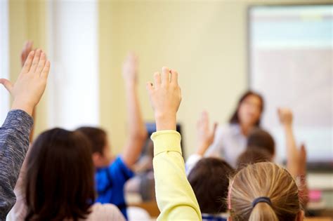 group of school kids raising hands in classroom | National Association ...