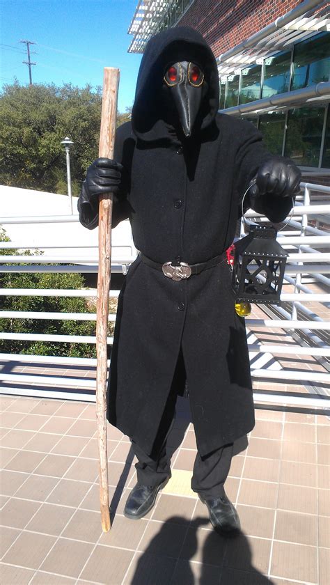 a person in a black outfit holding a stick and wearing a mask with red eyes