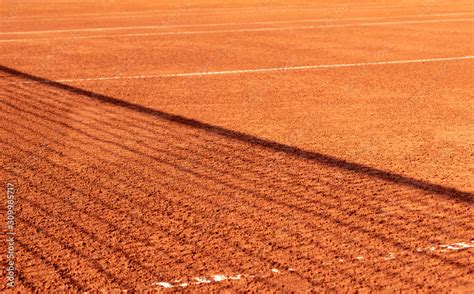 Clay tennis court with a net shadow on it. Outdoor red tennis court ...