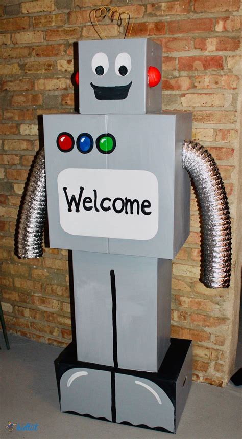 a welcome sign is placed on top of a small robot statue in front of a ...