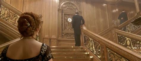 a woman in a black dress is walking down the stairs with a man in a ...