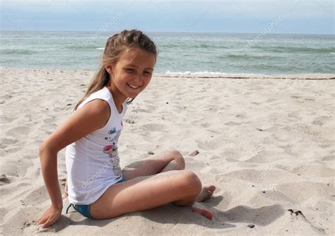 Smiling girl sitting on the beach Stock Photo by ©tory 27033519