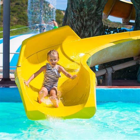 Premium Photo | Little girl on water slide at aquapark during summer ...