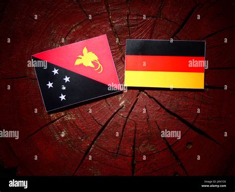 Papua New Guinea flag with German flag on a tree stump isolated Stock ...