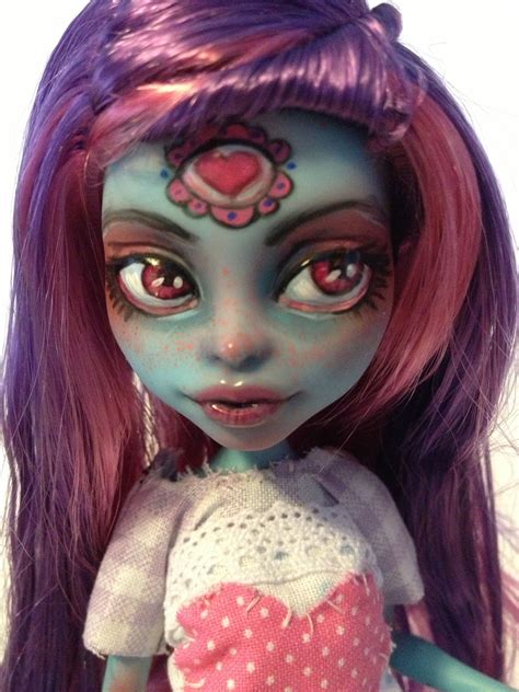 a close up of a doll with purple hair and green eyes wearing a pink dress