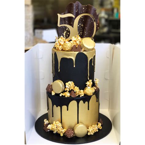 Black and gold two tier with caramel popcorn, macarons, chocolate drip ...