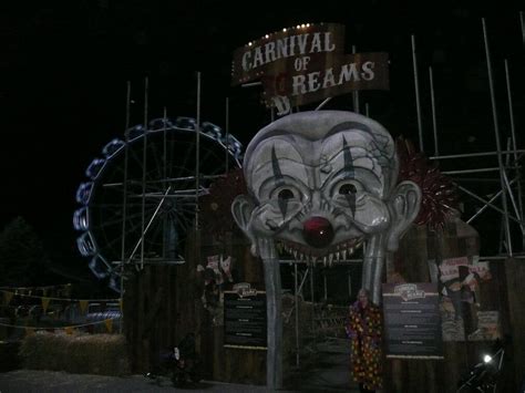 a carnival sign with a creepy clown's face on it and a ferris wheel in ...