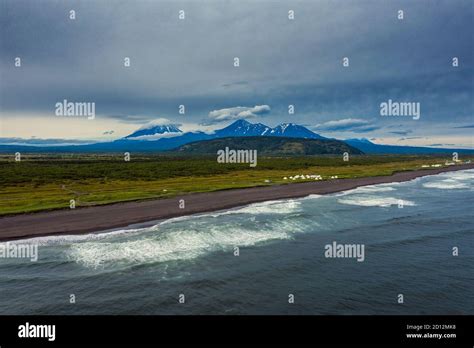 Beach with black sand and volcano Stock Photo - Alamy