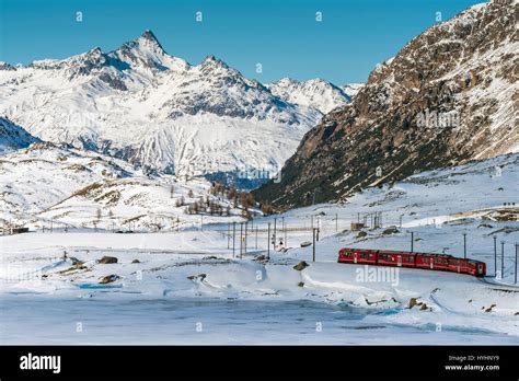 Bernina Express red train passing Lago Bianco in a scenic winter ...