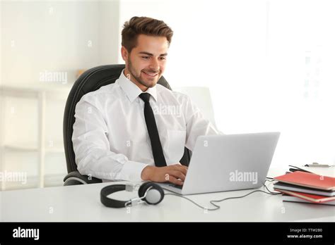 Handsome young man working on laptop in office Stock Photo - Alamy