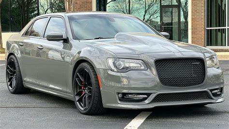 the front end of a gray car parked in a parking lot next to a building