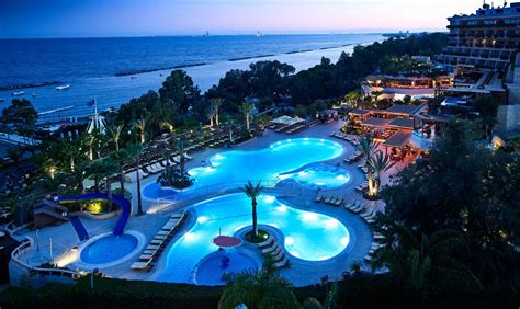 an aerial view of a resort pool at night with the ocean in the back ground