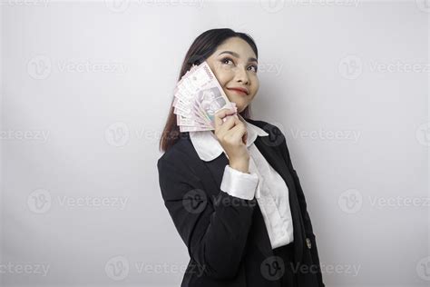 A thoughtful young woman is wearing black suit and holding cash money ...