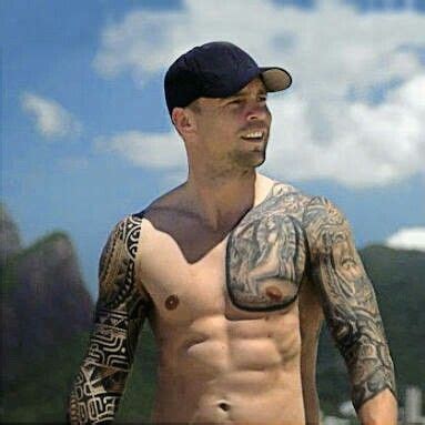 a shirtless man with tattoos on his chest and arm is standing in front ...