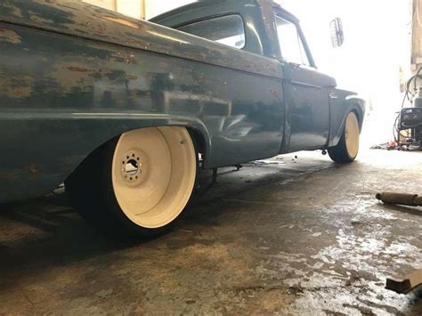 an old blue truck parked in a garage next to a wrench on the ground