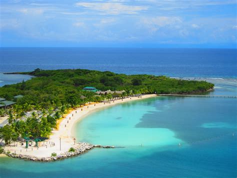 an island in the middle of blue water with palm trees on it and people ...