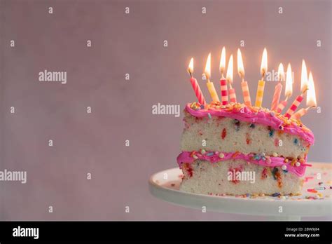 Slice of birthday cake with lit candles Stock Photo - Alamy