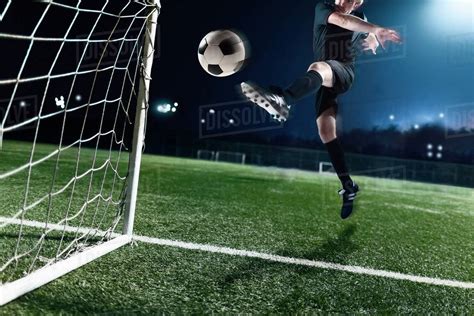 Athlete kicking soccer ball into a goal - Stock Photo - Dissolve