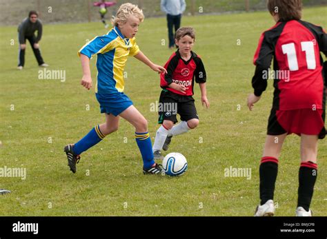 Three young kids children teenage boys playing football soccer game ...