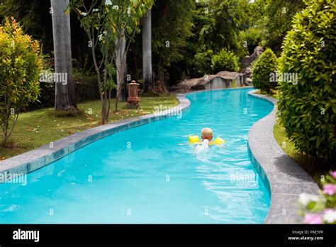 Baby in swimming pool with yellow swim aid. Child with float wings. Kid ...