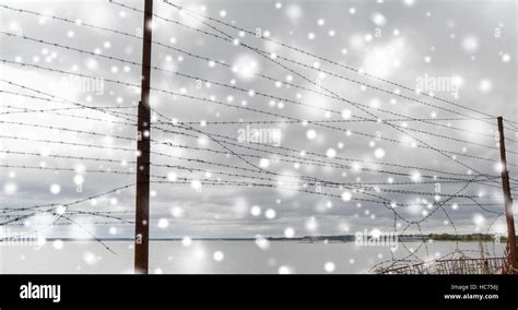 broken barb wire fence over gray sky and sea Stock Photo - Alamy