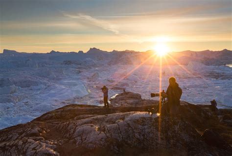 Three photographers taking pictures of icebergs during sunset in the ...