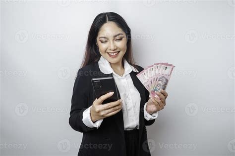 A happy young businesswoman is wearing black suit, holding her phone ...