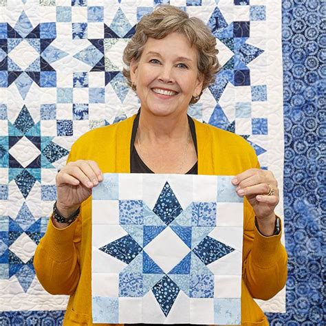 a woman holding up a blue and white quilt