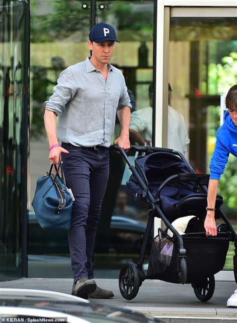 Tom Hiddleston is the doting father as he pushes his baby's pram ...