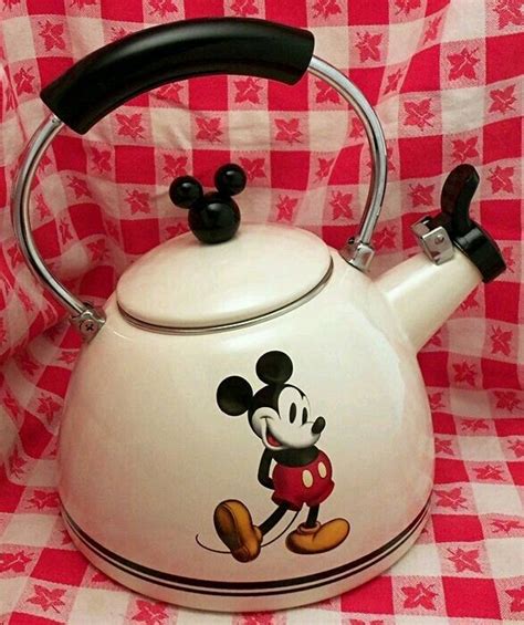 a mickey mouse tea kettle sitting on top of a checkered table cloth