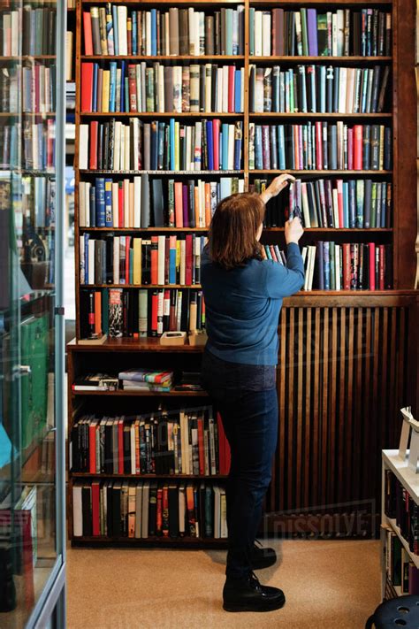 Rear view of librarian arranging books on shelf in store - Stock Photo ...