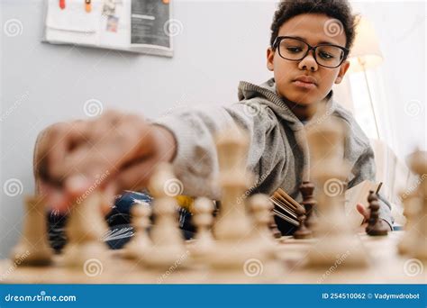 Black Boy in Eyeglasses Playing Chess while Sitting on Sofa Stock Photo ...